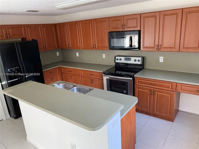 kitchen featuring a sink, an island with sink, brown cabinetry, light tile patterned floors, and black appliances