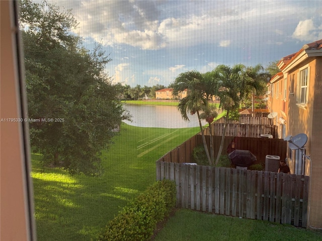 view of yard with a water view, fence, and central AC unit