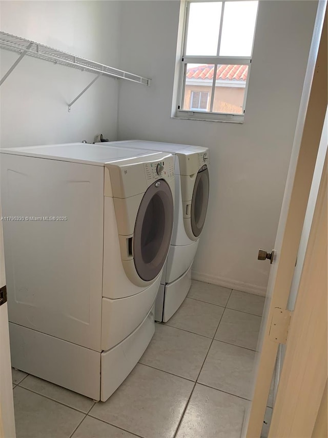 washroom with baseboards, laundry area, light tile patterned flooring, and washing machine and clothes dryer