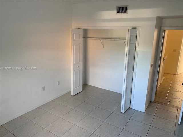 unfurnished bedroom featuring visible vents, baseboards, light tile patterned floors, and a closet