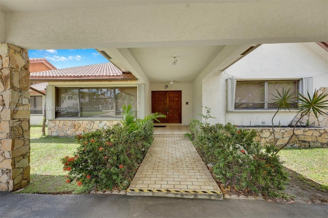 view of exterior entry featuring stucco siding and a tile roof