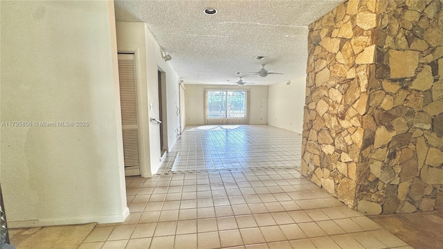hallway with a textured ceiling, visible vents, and light tile patterned floors