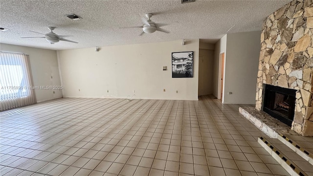 unfurnished living room with a stone fireplace, a ceiling fan, a textured ceiling, and visible vents