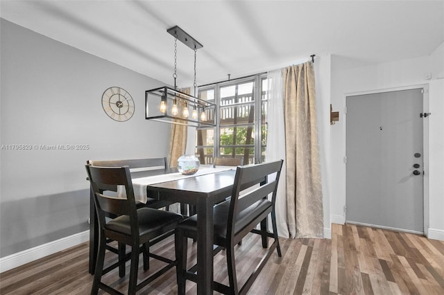 dining space with baseboards and wood finished floors