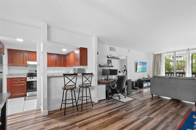 kitchen with stainless steel electric range, a sink, light wood finished floors, open floor plan, and visible vents