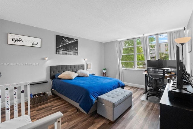 bedroom featuring baseboards, a textured ceiling, and wood finished floors
