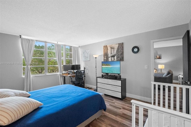 bedroom featuring baseboards, a textured ceiling, and wood finished floors