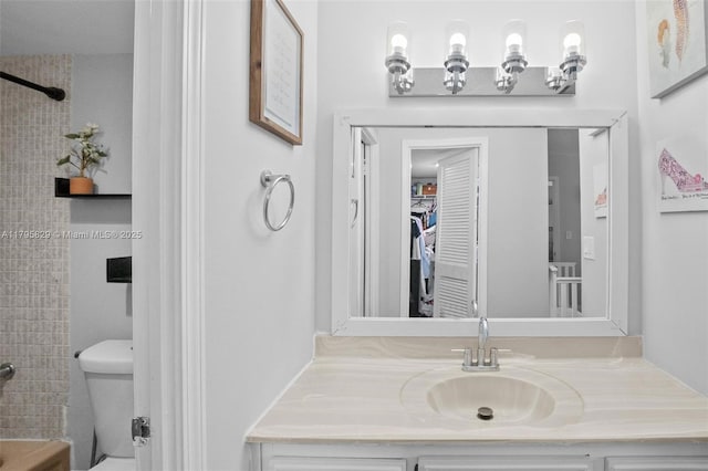 bathroom featuring toilet, a shower, and vanity
