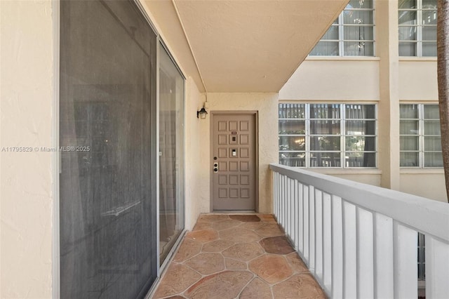 view of exterior entry with a balcony and stucco siding