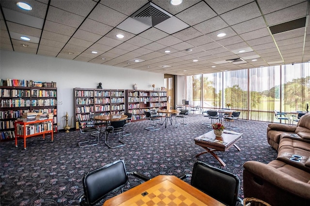 interior space with carpet flooring, bookshelves, recessed lighting, floor to ceiling windows, and visible vents