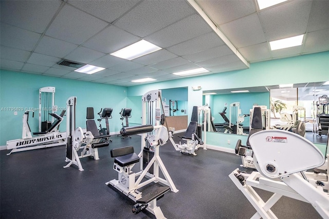 gym featuring baseboards and a paneled ceiling