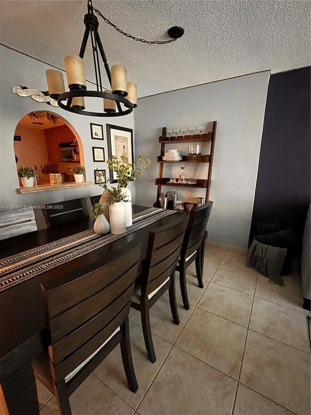 401 Ocean Dr Unit 324, Miami Beach, FL 33139 - tiled dining area featuring a textured ceiling, a chandelier, and a bar