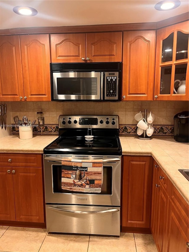 401 Ocean Dr Unit 324, Miami Beach, FL 33139 - kitchen featuring appliances with stainless steel finishes, tile countertops, light tile patterned flooring, and decorative backsplash