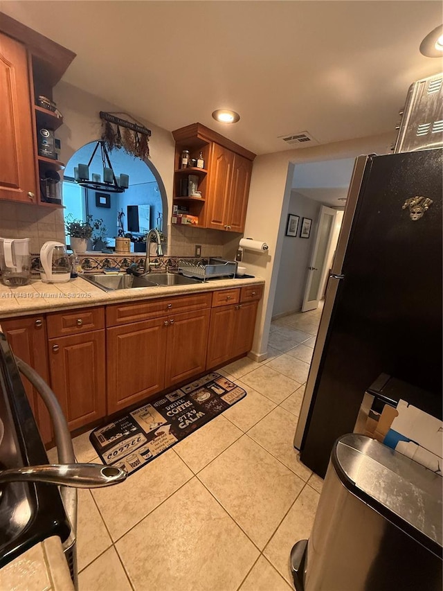 401 Ocean Dr Unit 324, Miami Beach, FL 33139 - kitchen with open shelves, light countertops, light tile patterned floors, freestanding refrigerator, and brown cabinetry