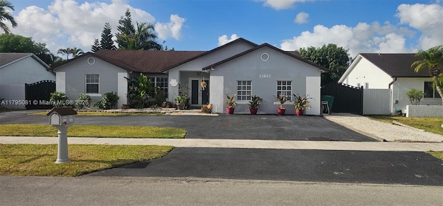 ranch-style home featuring stucco siding, fence, and a gate