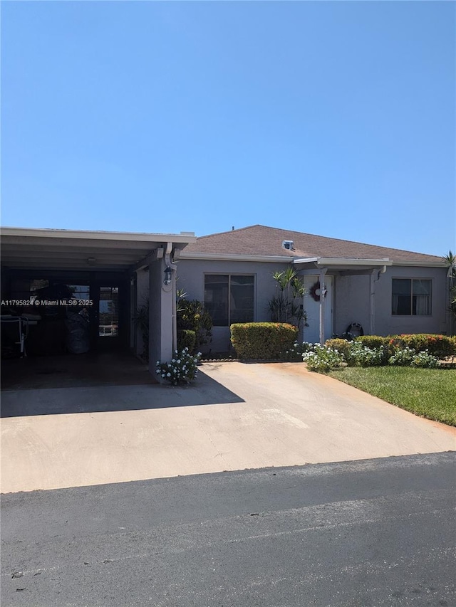 view of front facade featuring concrete driveway, a carport, and stucco siding