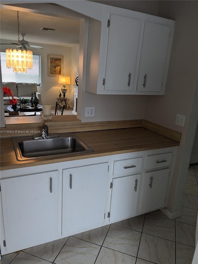 kitchen with a sink, white cabinetry, marble finish floor, and visible vents