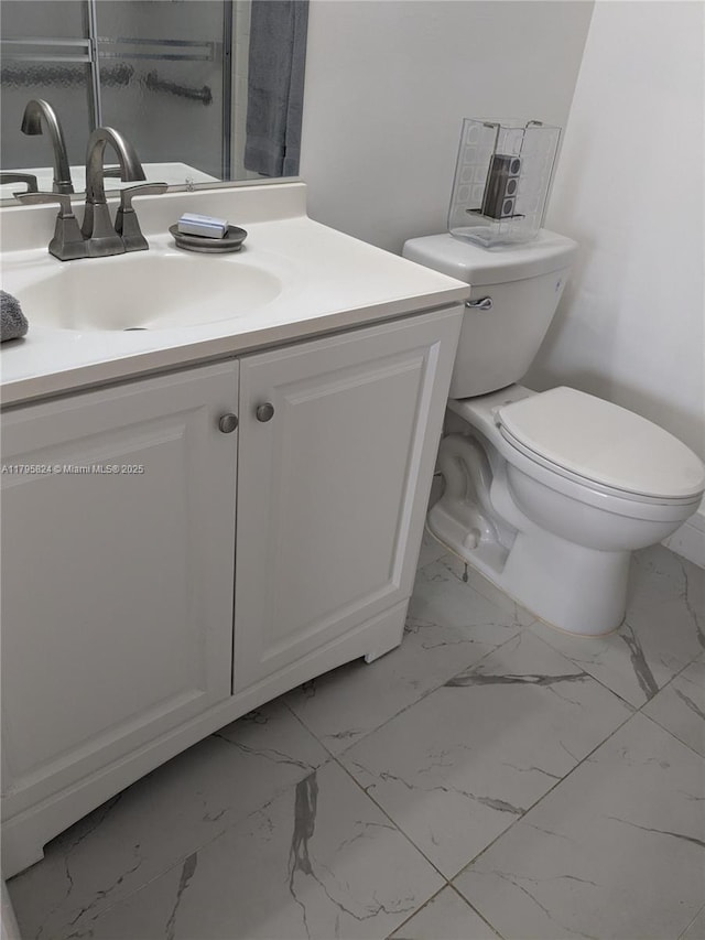 bathroom with vanity, toilet, and marble finish floor
