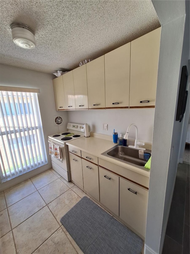 kitchen with white range with electric cooktop, light countertops, a textured ceiling, a sink, and light tile patterned floors