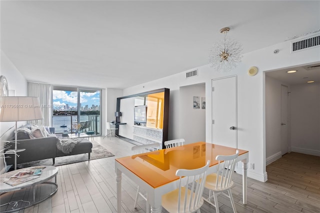 dining area featuring visible vents, a wall of windows, light wood-style flooring, and an inviting chandelier