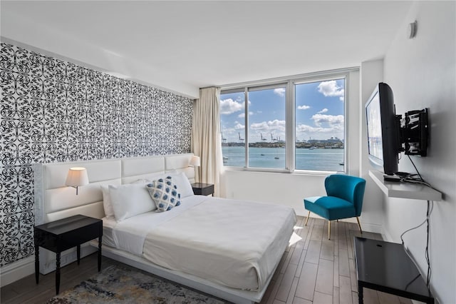 bedroom with baseboards, wood finished floors, and wallpapered walls