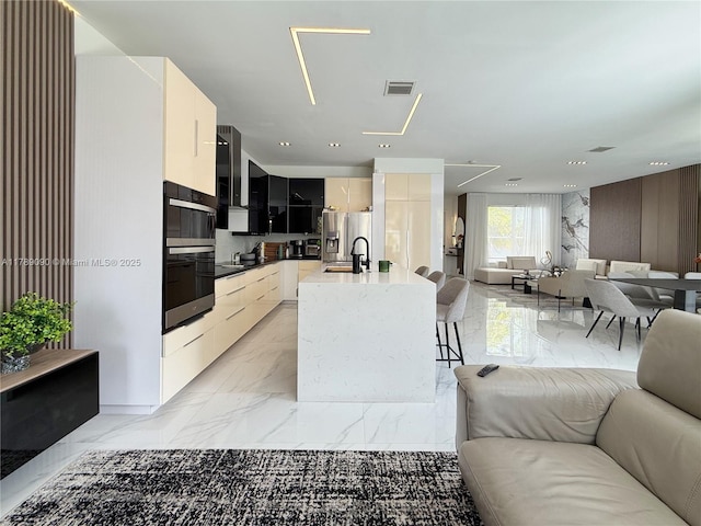 kitchen featuring modern cabinets, marble finish floor, visible vents, and open floor plan