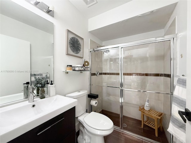 full bath featuring vanity, a stall shower, toilet, and visible vents