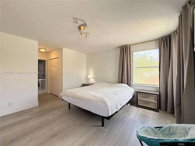 bedroom with baseboards, a closet, and light wood finished floors