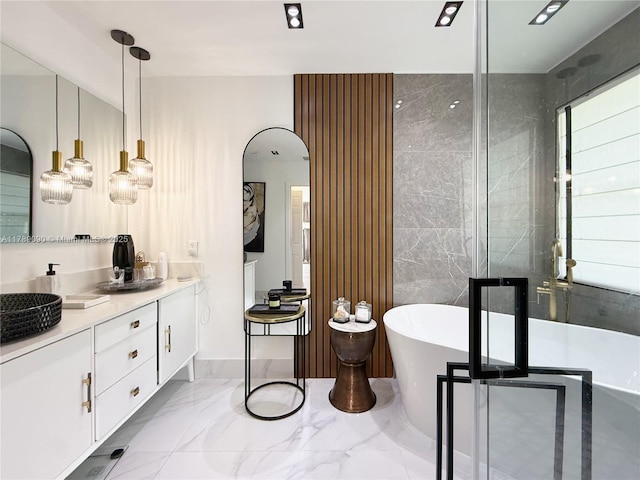 bathroom with a freestanding bath, vanity, and marble finish floor