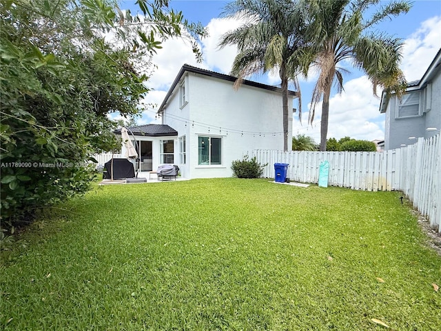 rear view of property featuring a yard, a fenced backyard, a patio area, and stucco siding