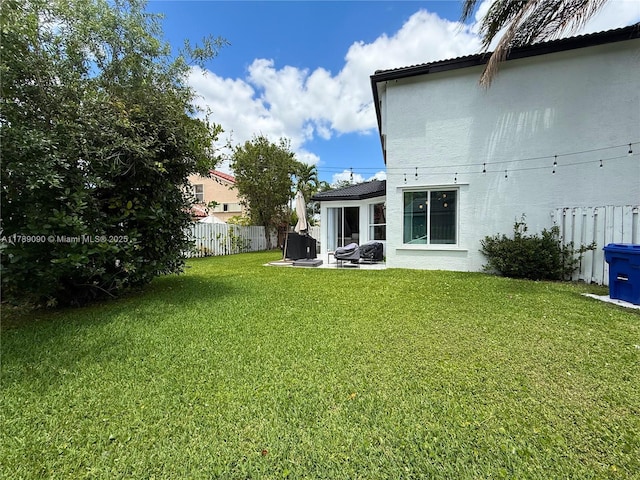 rear view of house featuring fence, stucco siding, a lawn, and a patio area