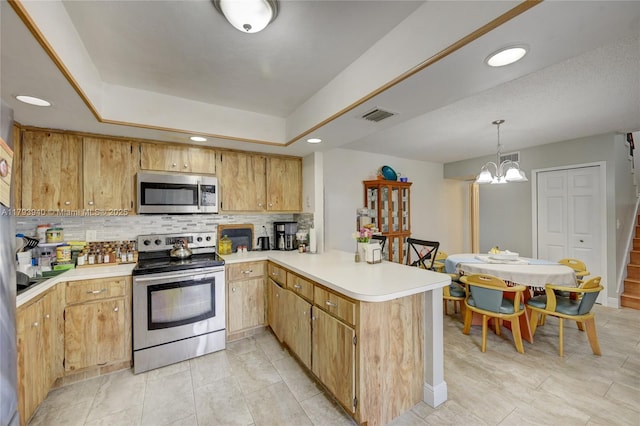 12079 W Regal Ct W, Wellington, FL 33414 - kitchen featuring stainless steel appliances, a peninsula, decorative backsplash, light countertops, and a chandelier
