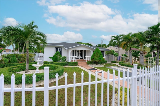 view of front facade featuring a shingled roof, a fenced front yard, stucco siding, and french doors