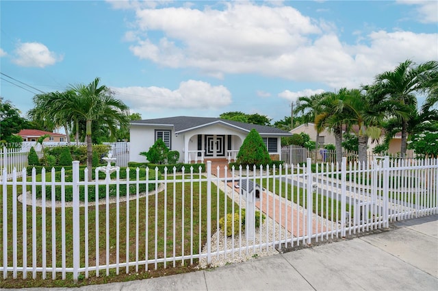 ranch-style home featuring driveway, a fenced front yard, a front yard, and stucco siding