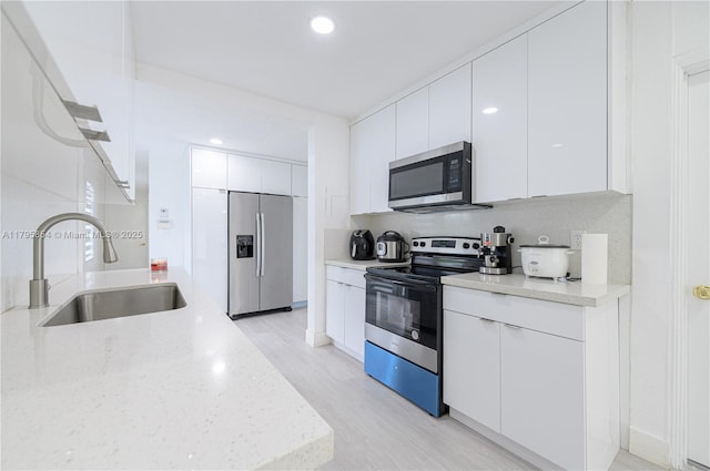 kitchen with white cabinets, appliances with stainless steel finishes, a sink, and modern cabinets