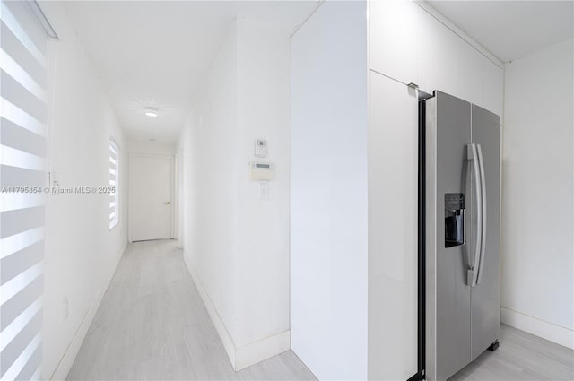 corridor featuring baseboards and light wood-style flooring