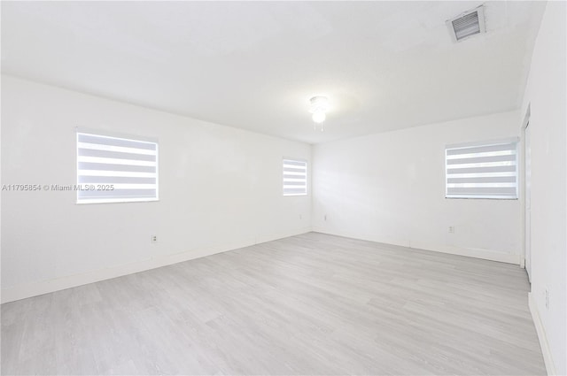 spare room with visible vents, baseboards, and wood finished floors