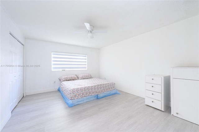 bedroom featuring a closet, a ceiling fan, baseboards, and light wood-type flooring
