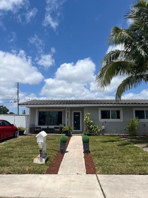 single story home with stucco siding, a tile roof, and a front yard