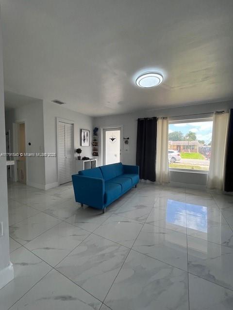 living area featuring visible vents, marble finish floor, and baseboards