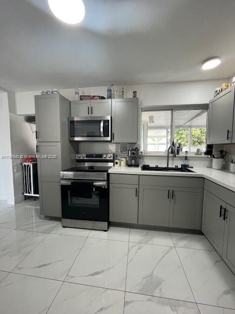 kitchen featuring a sink, gray cabinets, appliances with stainless steel finishes, and marble finish floor