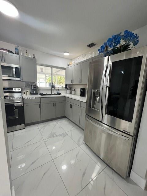kitchen with visible vents, marble finish floor, gray cabinets, a sink, and stainless steel appliances