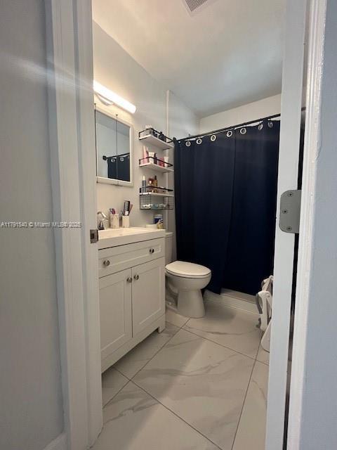 bathroom with vanity, a shower with shower curtain, toilet, and marble finish floor
