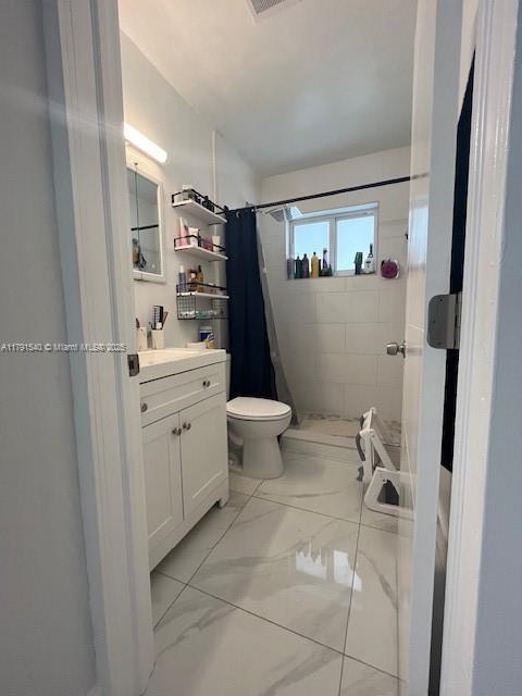 bathroom featuring vanity, marble finish floor, toilet, and a shower stall