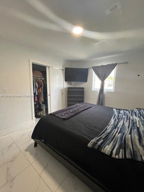 bedroom featuring a closet and marble finish floor