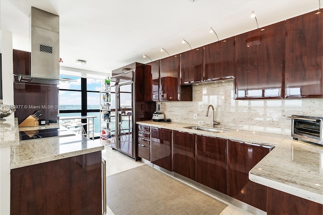 kitchen featuring a sink, decorative backsplash, black electric cooktop, extractor fan, and light stone countertops