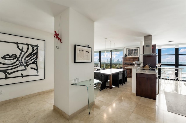 kitchen featuring island exhaust hood, floor to ceiling windows, light countertops, light tile patterned floors, and baseboards