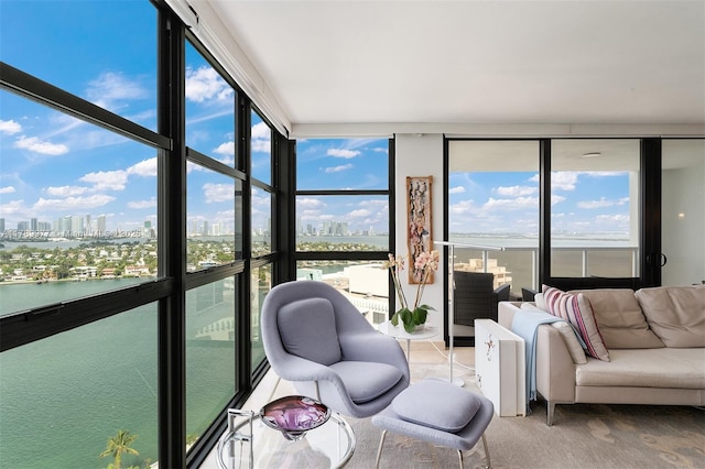 sunroom / solarium with a view of skyline, a water view, and a wall of windows