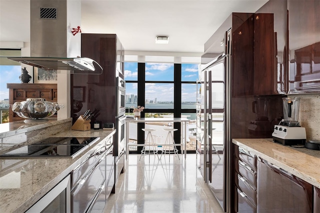 kitchen with island range hood, a wall of windows, black electric cooktop, and light stone counters
