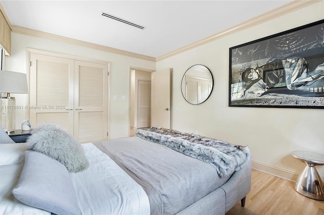 bedroom with visible vents, ornamental molding, a closet, wood finished floors, and baseboards